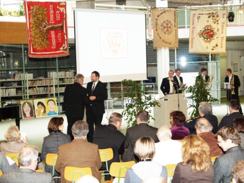 Das Bild zeigt Herrn Oberbürgermeister Gerd Hager mit dem 1. Vorsitzenden Klaus Link. Im Hintergrund das Bläserensemble der Jugendmusikschule.